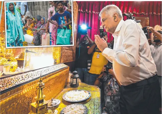  ?? Pictures: AFP ?? New Prime Minister Ranil Wickremesi­nghe offers prayers after his swearing in ceremony as people queue for supplies (inset).