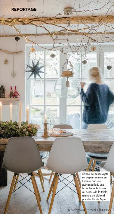  ??  ?? Ornée de petits sujets en papier et mise en lumière par une guirlande led, une branche se balance au-dessus de la table, retenue au plafond par des fils de Nylon.