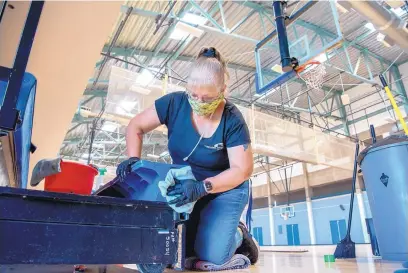  ?? EDDIE MOORE/JOURNAL ?? Gina Noriega, lead worker at the Genoveva Chavez Community Center, helps deep clean the bleachers around the basketball arena. She is one of many employees currently furloughed for 16 hours per week.