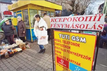  ?? SERGIY GUDAK/AFP ?? Local residents walk next to an advertisin­g poster on Hungarian language in Beregove, a small town in western Ukraine, on November 15.