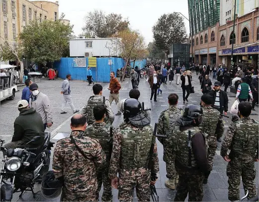  ?? ?? Policías iraníes patrullan en el centro de Teherán mientras ciudadanos caminan junto a tiendas cerradas, esta semana.