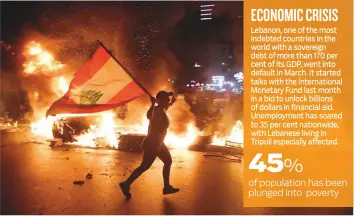  ?? AFP ?? A protester holding the Lebanese flag runs as protesters block Jounieh Tripoli highway with tyres set aflame during a demonstrat­ion in Jal Al Dib, north-east of the capital Beirut, on Thursday.