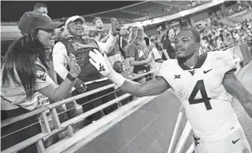  ?? RON JENKINS/AP ?? West Virginia running back Leddie Brown (4) celebrates with fans following a win over TCU on Oct. 23 in Fort Worth, Texas.