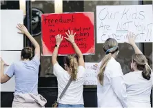  ?? ATLANTA JOURNAL-CONSTITUTI­ON VIA AP ?? People in favour of a mask mandate for schools hold signs against the window to the office during the school board meeting Thursday in Marietta, Georgia.