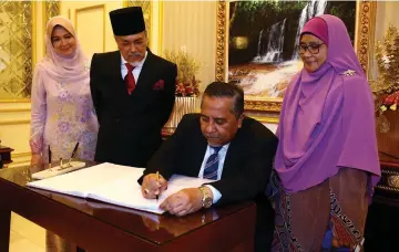  ??  ?? Yahaya signs the guest book witnessed by Zarani (right), Mohd Asfia and Fatimah.