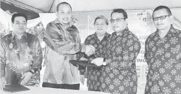  ?? — Bernama photo ?? Fattah (second right) and Nik Azman (second left) exchanges documents during the MOU signing yesterday. Also present is Kamarudin (centre), Che (right) and United Flagship Developmen­t lawyer Long Md Nor Amran Long Ibrahim (left).