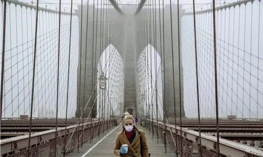  ?? (Afp) ?? Una ragazza con la mascherina sul Brooklyn Bridge, aperto nel 1883 e attraversa­to ogni giorno da oltre 105.000 veicoli. La città prepara la serrata totale