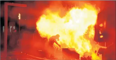  ??  ?? BLAZING BORDEAUX: A protester wearing a gas mask hurls a bin into a flaming barricade yesterday