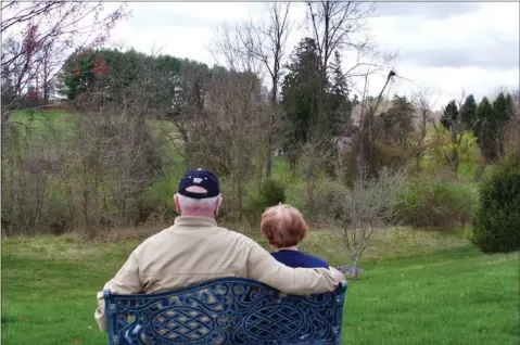  ?? SUBMITTED PHOTO ?? Bob and Pat Kostenbade­r sit on one of the benches set up outside — spaced far apart — to encourage The Heritage residents in Shillingto­n to enjoy the spring weather and the views.