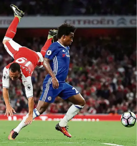  ?? — AP ?? Topsy-turvy: Arsenal’s Santi Cazorla falls after colliding with Chelsea’s Willian in the English Premier League match at the Emirates on Saturday. Arsenal won 3-0.