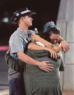  ??  ?? People hugging each other after a mass shooting at the Route 91 Harvest country music festival in Las Vegas on Sunday.