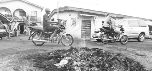  ??  ?? Taxi motorcycli­sts popularly called Okada drive past bonfires lit by vigilante to watch over their communitie­s.