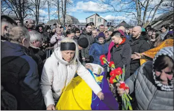  ?? Thibault Camus The Associated Press ?? Oksana Bondarenko adjusts the Ukrainian flag on the coffin of her brother, Vladyslav Bondarenko, 26, a paratroope­r who died near Bakhmut on Feb. 26.