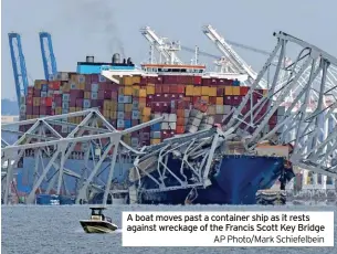  ?? ?? A boat moves past a container ship as it rests against wreckage of the Francis Scott Key Bridge