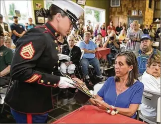  ?? SCOTT HECKEL / THE (CANTON) REPOSITORY ?? Marine Staff Sgt. Victoria Poland presents to her second cousin, Tina M. Hoffman, the war medals of Hoffman’s late father at the Ohio Veterans’ Memorial Park in Clinton on June 27. Hoffman was 3 years old when her father, Sgt. Ronald L. Poland, died in Vietnam.