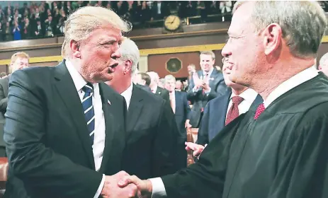  ?? Afp ?? DESACUERDO. El presidente Donald Trump estrecha la mano del jefe de la Corte Suprema John Roberts.