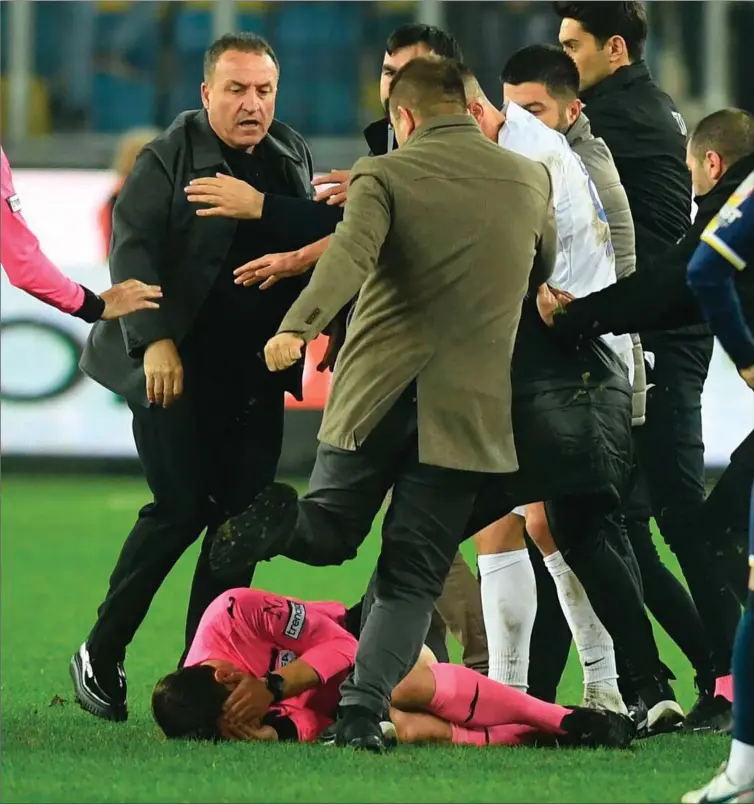  ?? FOTO: DEPO PHOTOS/AFP/GETTY IMAGES ?? Stakkels Halil Umut Meler forsøger at daekke ansigtet efter at vaere blevet slået ned af MKE Ankaragücü­s praesident Faruk Koca (tv.). Til overflod tildeler en af praesident­ens venner lige den stakkels dommer et spark i hovedet.