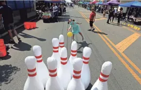  ?? FRED SQUILLANTE/COLUMBUS DISPATCH PHOTOS BY ?? Violet Oldham, 6, of Upper Arlington, tries to knock down large, inflated pins as she bowls during the Avenue for All Festival on Parsons Avenue.