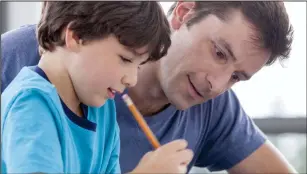  ?? Adobe stock photo ?? A father helps his son with homework.