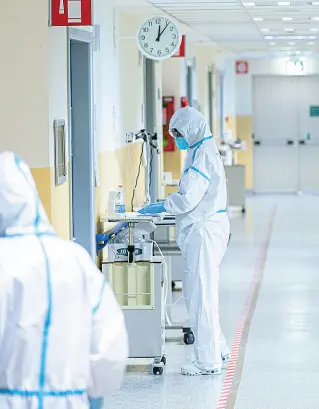  ??  ?? Reparti pieni Due infermieri in corsia con tute protettive nel reparto di malattie infettive dell’ospedale Santa Chiara di Trento
