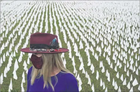  ?? THE ASSOCIATED PRESS ?? Artist Suzanne Brennan Firstenber­g stands among thousands of white flags planted in remembranc­e of Americans who have died of COVID-19 near Robert F. Kennedy Memorial Stadium in Washington last October.