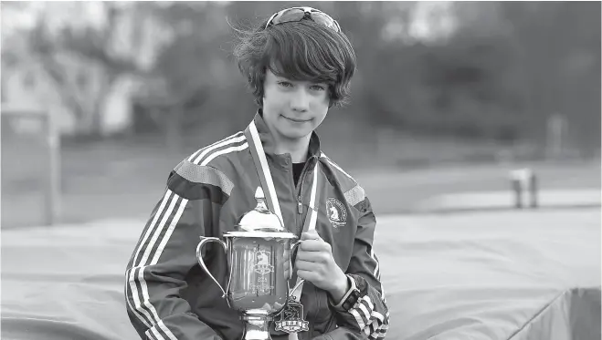  ?? John Woike/ Hartford Courant/TNS ?? Aidan Puffer of Manchester, Conn., age 13, broke his own world record for the fastest 13-year-old to run a 5K at the BAA 5K in Boston. Puffer is holding the trophy Hagos Gebrhiwet, the winner of the men’s BAA 5K road race, gave to him after his record...