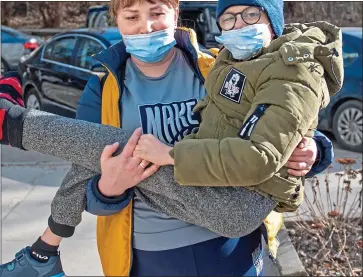  ?? ?? SAFETY: Nine-year-old Yaroslav is carried to the convoy by his mother