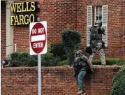 ?? Mike Stewart / Associated Press ?? Police officers take up positions Friday outside a Wells Fargo Bank in Marietta, Ga., where a man held two hostages.