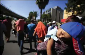  ?? AP PHOTO/REBECCA BLACKWELL ?? A sleeping Honduran girl is carried as a group of Central American migrants, representi­ng the thousands participat­ing in a caravan trying to reach the U.S. border, undertake an hours-long march to the office of the United Nations’ humans rights body in Mexico City on Thursday. Members of the caravan which has stopped in Mexico City demanded buses Thursday to take them to the U.S. border, saying it is too cold and dangerous to continue walking and hitchhikin­g.