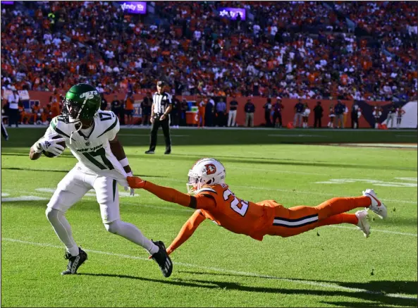  ?? ANDY CROSS — THE DENVER POST ?? New York Jets wide receiver Garrett Wilson eludes a tackle attempt by Broncos cornerback Damarri Mathis for a first down in the third quarter at Empower Field at Mile High on Sunday.