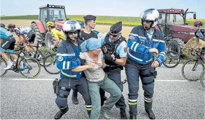  ?? AFP ?? Fuera del camino. Policías sacan de la ruta a una campesina que protestaba entre los ciclistas.