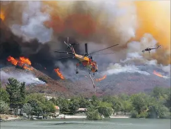  ?? Luis Sinco Los Angeles Times ?? A HELICOPTER helps fight the Blue Cut fire in Lytle Creek. The fire has scorched 30,000 acres of dry foothill and desert vegetation and led officials to order an estimated 80,000 people to evacuate.