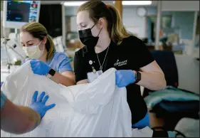  ?? ISADORA KOSOFSKY / THE NEW YORK TIMES ?? Nurse Bridget Klingenber­g, right, and colleagues move a patient in an intensive care unit for COVID-19 patients at Covenant HealthCare in Saginaw, Mich., Dec. 15, 2021. Some researcher­s are hopeful that omicron may cause less severe disease than delta, but the new variant arrives at a moment when there is little capacity left in hospitals, especially in the Midwest and Northeast.