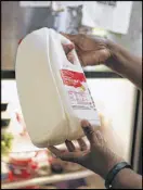  ?? EMILY JENKINS / EJENKINS@AJC.COM ?? A jug of milk is inspected in Ligaya Figueras’ refrigerat­or.