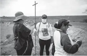  ?? FELIX MARQUEZ/AP 2019 ?? Lidia Lara Tobon, center, whose brother went missing, works with others searching for clandestin­e graves at a municipal dump.