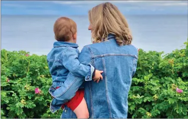  ?? ALEX RICHER VIA AP ?? This photo provided by Alex Richer shows his wife, AP writer Alanna Durkin Richer, holding one of their children at Cape Cod on July 4, 2021. In the aftermath of the May Uvalde, Texas, school shooting, she writes, ‘I know rationally that I can’t keep my almost 3-year-old son and his 7-month-old sister in a bubble all their lives. No matter how hard I try, I won’t always be able to protect them from harm and pain. But why should I have to fear simply sending them to school?’