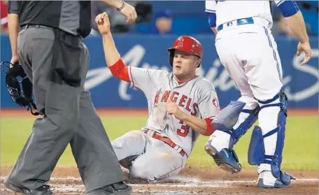  ?? Tom Szczerbows­ki Getty Images ?? NICK BUSS of the Angels slides across home plate to score a run on a two-run single by Mike Trout in the seventh inning.