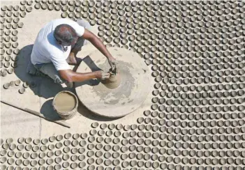  ?? — Reuters ?? A man makes earthen lamps which are used to decorate temples and homes during the festival of Diwali on a street in Ajmer on Saturday.