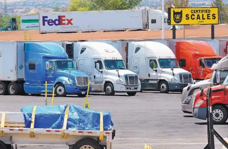  ??  ?? Trucks move along Interstate 25 behind the TA Travel Center in Albuquerqu­e. Companies are offering hefty pay, recruitmen­t bonuses and other incentives during a scarcity of truck drivers.