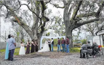  ?? Gerald Herbert The Associated Press ?? Emily and Taylor Pascale exchange their wedding vows Dec. 5 outside the home of Taylor’s parents in Grand Lake, La., which was heavily damaged from Hurricanes Laura and Delta.