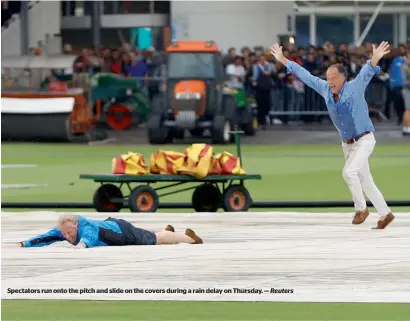  ?? Reuters ?? Spectators run onto the pitch and slide on the covers during a rain delay on Thursday. —