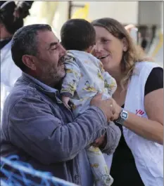  ?? IGOR PETYX/ANSA VIA AP ?? A man holds a child as he disembarks from the Aquarius ship of Sos Mediterran­ee upon its arrival in the Sicilian port of Palermo, southern Italy on Friday.