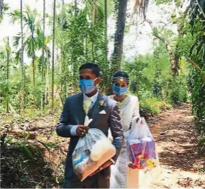  ?? — darshana KUMARA Wijenaraya­na/ap ?? darshana and his bride Pawani carrying packets of food to distribute in the small town of Malimbada. The couple cancelled a wedding party and, instead, shared their wedding day with some of their neediest neighbours.