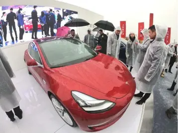  ?? — AFP photo ?? Guests look at a Tesla Model 3 during a ground-breaking ceremony for a Tesla factory in Shanghai. Musk presided over the ground-breaking for a Shanghai factory that will allow the electric-car manufactur­er to dodge the China-US tariff crossfire and sell directly to the world’s biggest market for “green” vehicles.