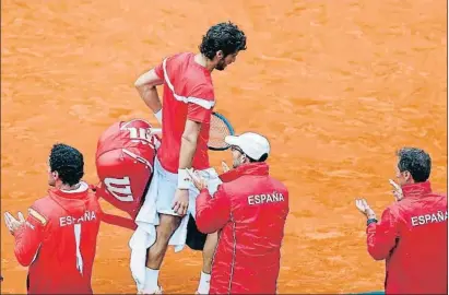  ?? KAI FÖRSTERLIN­G / EFE ?? Feliciano López, cabizbajo, se retira de la pista entre los aplausos de los integrante­s del equipo español