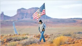  ?? RICK BOWMER/ASSOCIATED PRESS ?? Brandon Nez displays his flag Oct. 25 in Monument Valley, Utah. Navajo voters in one Utah county could tip the balance of power in the first general election since a federal judge ordered overturned their voting districts as illegally drawn to minimize native voices.
