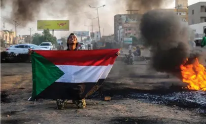  ?? Photograph: Mohammed Abu Obaid/EPA ?? A protester holds the Sudanese flag next to burning tyres during a demonstrat­ion against the coup in the capital, Khartoum, on Tuesday.