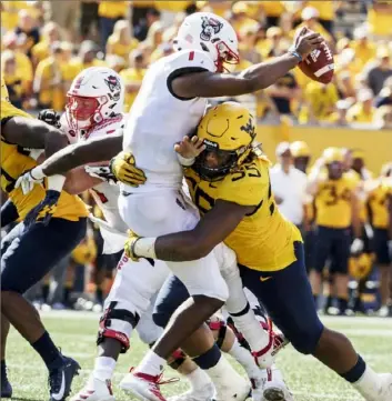  ?? Associated Press photos ?? West Virginia’s Dante Stills sacks N.C. State quarterbac­k Matthew McKay Saturday in the second half of a non-conference game in Morgantown, W.Va.