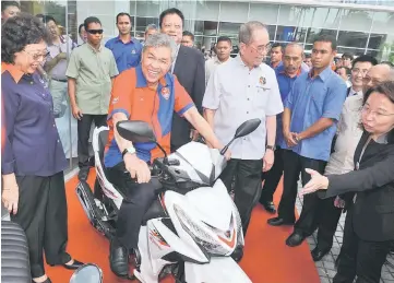  ??  ?? Ahmad Zahid riding the bike during the launch of Demak Motorcycle­s’ latest model at DNC Asiatic Holdings. Also seen are Wan Junaidi (third right) and Feona (left). — Bernama photo