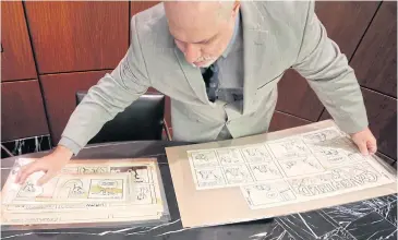  ?? PHOTOS BY AP ?? Heritage Auctions’ collectibl­es specialist Brian Wiedman displays Garfield comic artwork drawn by creator Jim Davis in Dallas.
